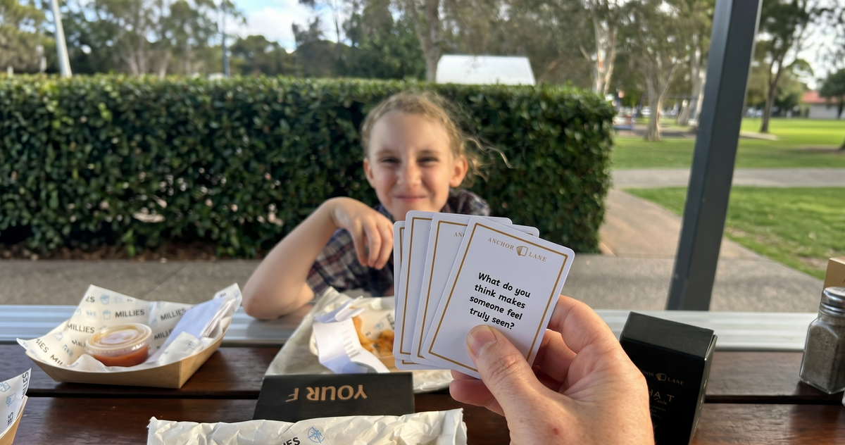 A dad and his daughter sitting together at a park table, sharing fish and chips