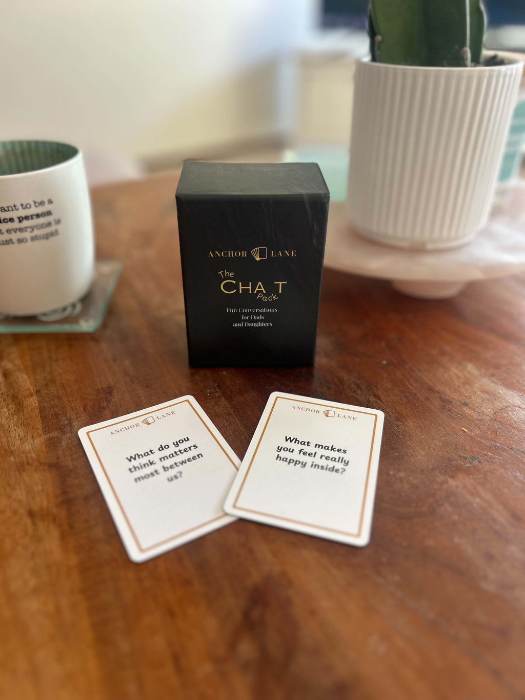 The Chat Pack deck by Anchor Lane on a kitchen table with two question cards laid out in front